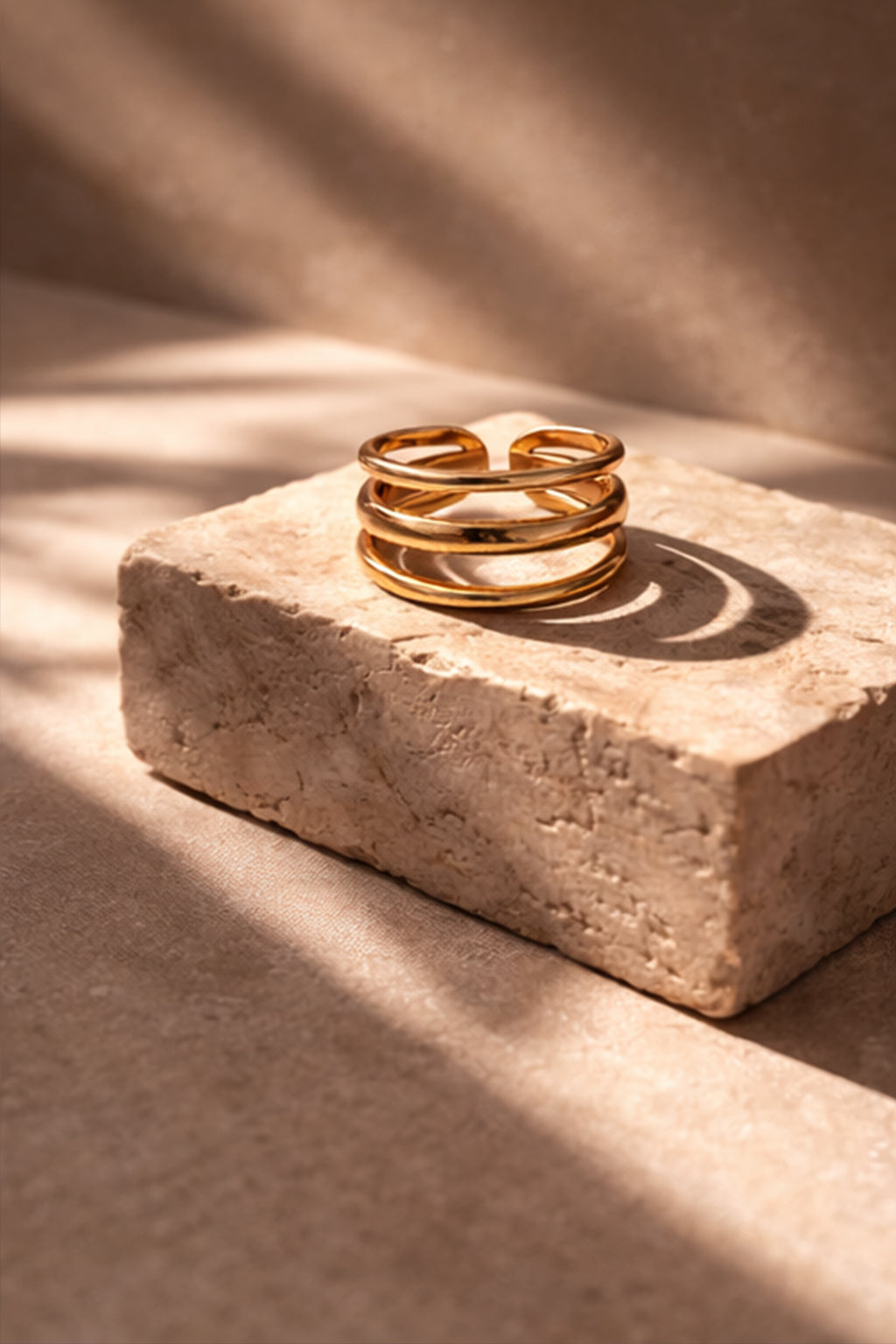 Gold ring on a textured stone surface with soft shadows