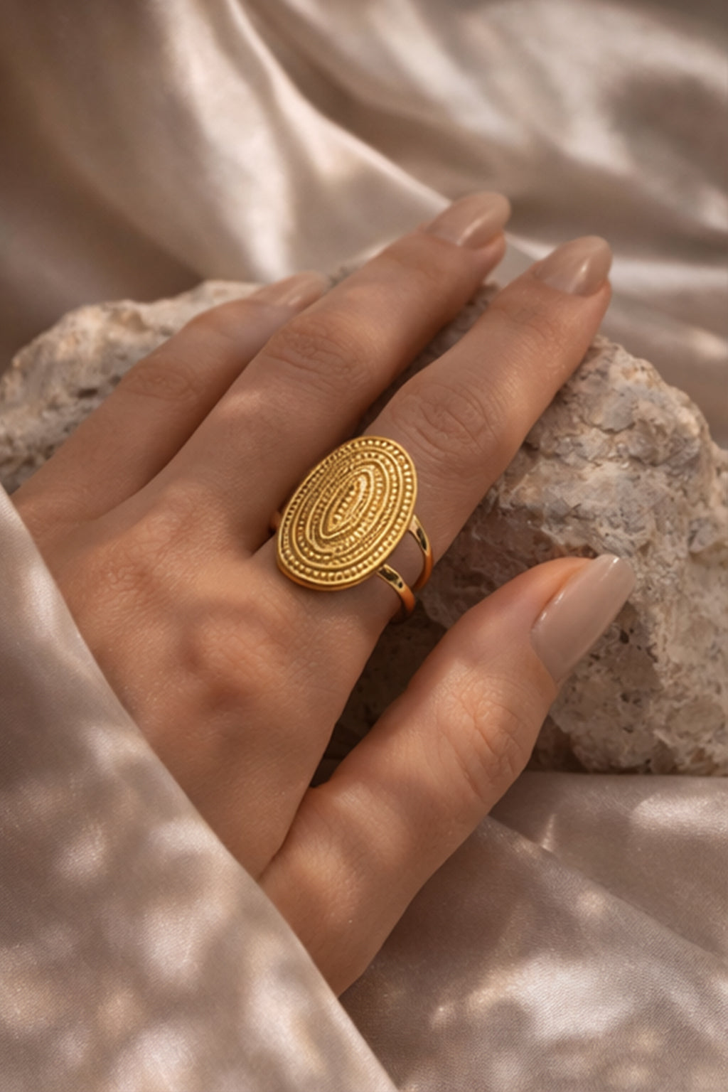 Gold ring on a hand with a neutral background